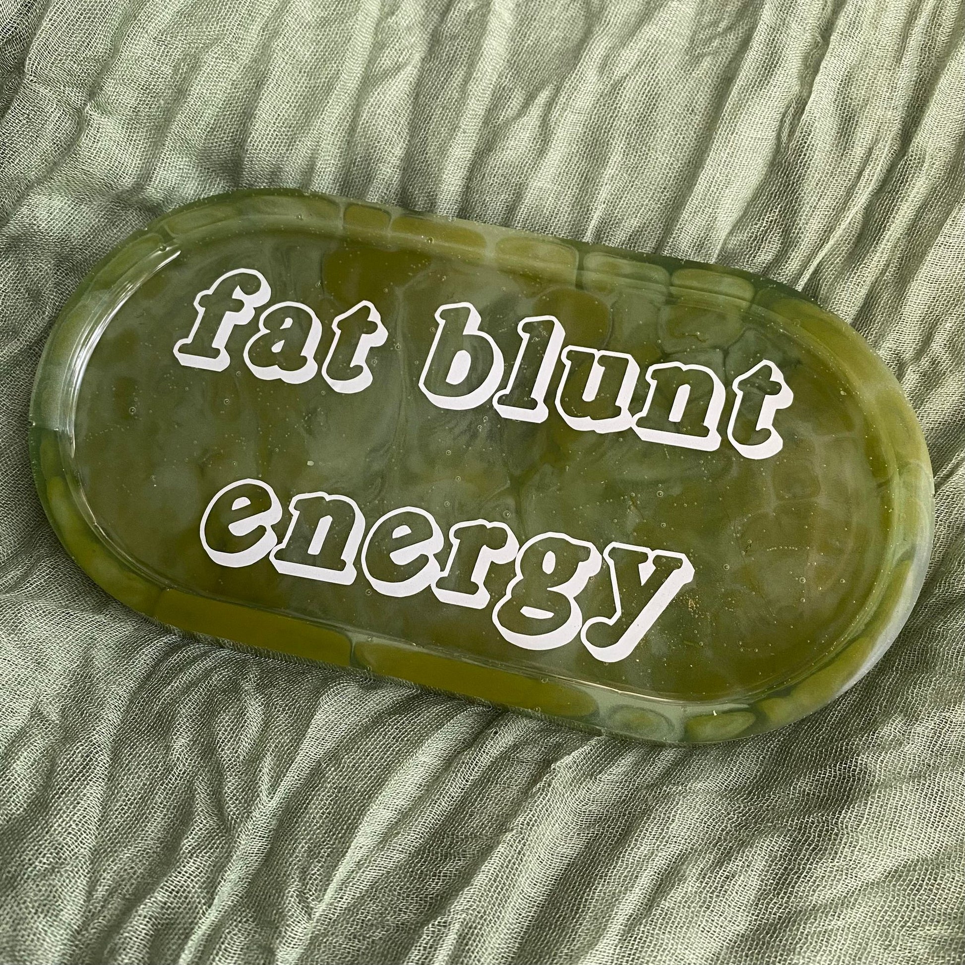 Photo shows an oval-shaped, green marbled resin tray with the words "fat blunt energy" on it.